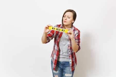 Young concerned beautiful woman in casual clothes using building bubble spirit level isolated on white background. Instruments, accessories, tools for renovation apartment room. Repair home conceptの写真素材