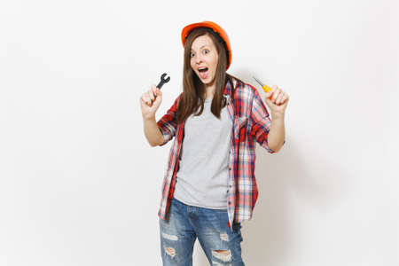 Young shocked beautiful woman in protective construction orange helmet holding toy screwdriver and...