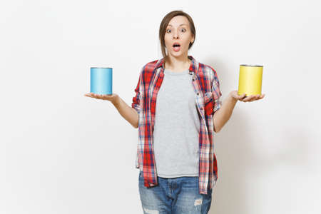 Young shocked beautiful woman in casual clothes holding empty paint tin cans with copy space...