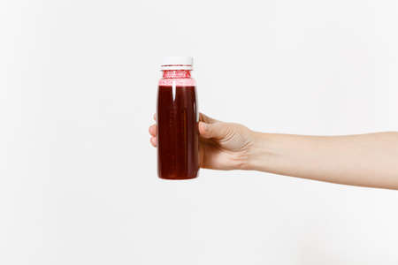 Close up female holds in hand dark red detox smoothies in bottle isolated on white background.