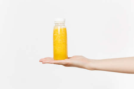 Close up female holds in hand on palm yellow detox smoothies in bottle isolated on white background.