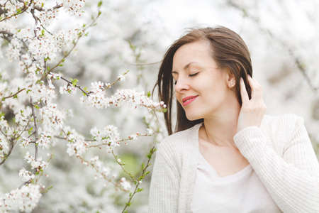 Young smiling relaxed tender beautiful woman with closed eyes in light casual clothes standing in...