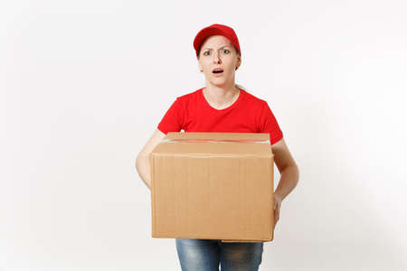 Delivery tired sad woman in red uniform isolated on white background. Female in cap, t-shirt, jeans working as courier or dealer holding cardboard box. Receiving package. Copy space for advertisementの写真素材