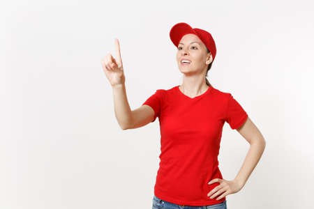 Delivery woman in red uniform touch something like click on button isolated on white background. Female in cap, t-shirt, jeans working as courier or dealer, pointing floating screen. Copy spaceの写真素材
