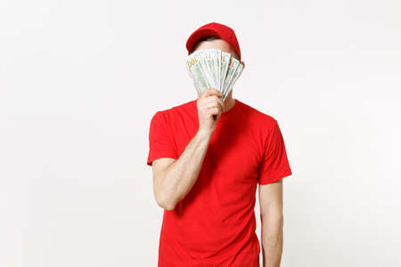 Delivery man in red uniform isolated on white background. Professional male in cap, t-shirt working as courier or dealer, holding bundle of dollars, cash money. Copy space for advertisementの写真素材