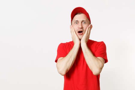 Delivery man in red uniform isolated on white background. Professional shocked caucasian male in cap, t-shirt working as courier or dealer, put hands on face gesture. Copy space for advertisement.の写真素材