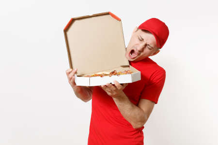 Delivery smiling man in red uniform isolated on white background. Male pizzaman in cap, t-shirt working as courier or dealer holding italian pizza in cardboard flatbox. Copy space for advertisementの写真素材