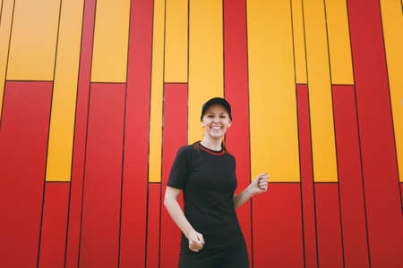 Young laughing athletic beautiful brunette girl in black uniform and cap dancing and resting before...