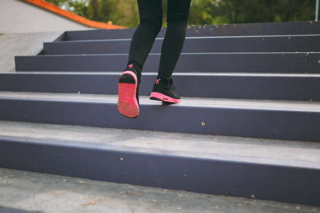 Cropped close up of woman legs in sportswear, black and pink sneakers doing sport exercises,...