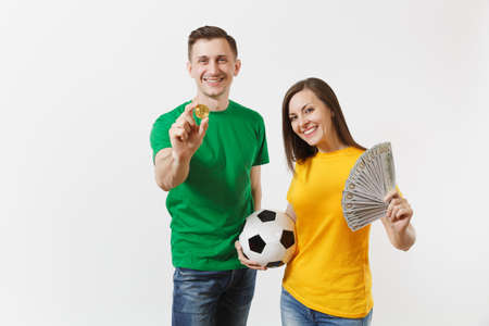 Smiling young couple woman man, football fans in yellow green t-shirt cheer up support team with soccer ball bitcoin, golden coin isolated on white background. Sport family leisure lifestyle concept.の写真素材