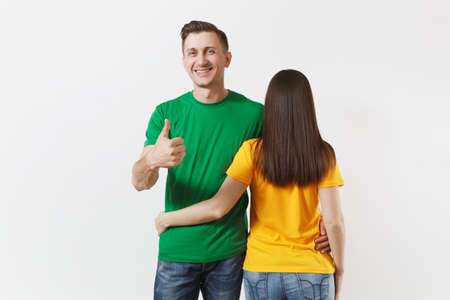 European young brunette woman, smiling man showing thumbs up, football fans in yellow green empty...