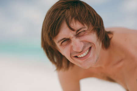 The handsome man with long hair smiling at the beachの写真素材