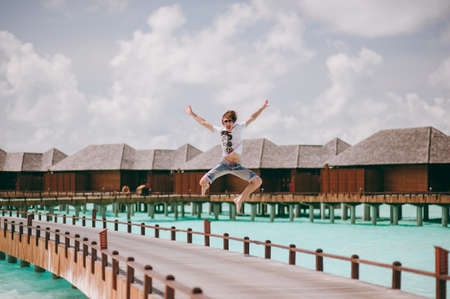 The young guy jumping up on the pierの写真素材
