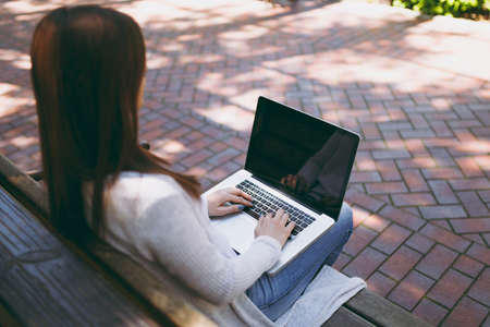 Close up cropped successful female hands on keyboard. Woman sitting on bench working on modern...