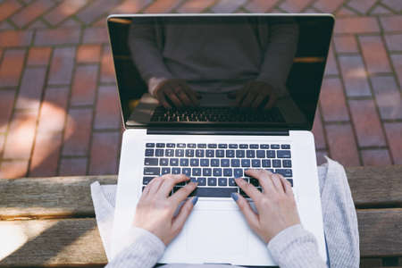Close up cropped successful female hands on keyboard. Woman sitting on bench working on modern...