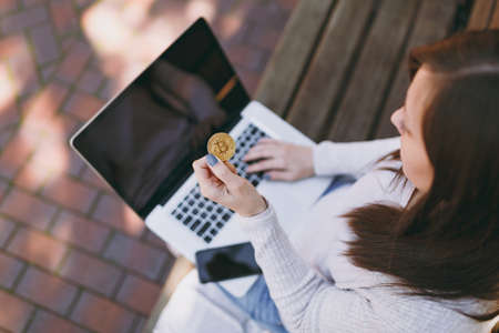 Close up female hands on keyboard. Woman sitting on bench working on modern laptop with blank empty...