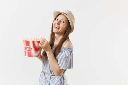 Young woman in blue dress, hat watching movie film holding eating popcorn from bucket isolated on white background. People, sincere emotions in cinema, lifestyle concept. Advertising area. Copy spaceの写真素材