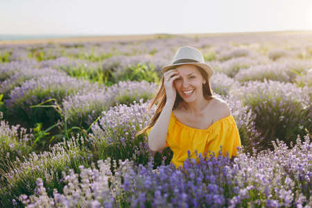 Portrait of young sensual beautiful woman in yellow dress on purple lavender flower blossom meadow field outdoors on summer nature background. Tender female near flowering bush. Lifestyle conceptの写真素材