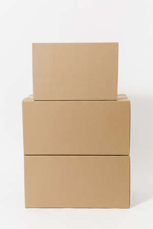 Stacked of three brown clear empty blank cardboard boxes isolated on white background. Receiving package. Copy space for advertisement. With place for text. Advertising area with workspaceの写真素材