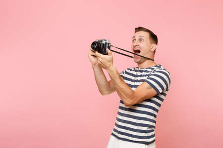 Portrait of smiling young photographer man wearing striped t-shirt take pictures on retro vintage...