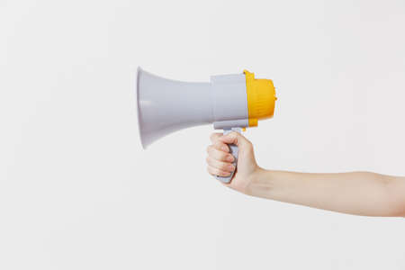 Close up female holds in hand bullhorn public address megaphone isolated on white background. Hot news, announce discounts sale, communication concept. Copy space. Advertising areaの写真素材