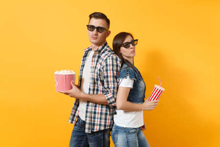 Young couple woman man in 3d glasses watching movie film on date holding bucket of popcorn plastic...