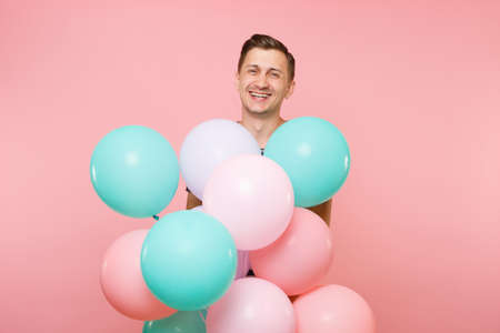 Portrait of fascinating young happy man wearing striped t-shirt holding colorful air balloons isolated on bright trending pink background. People sincere emotions lifestyle concept. Advertising areaの写真素材