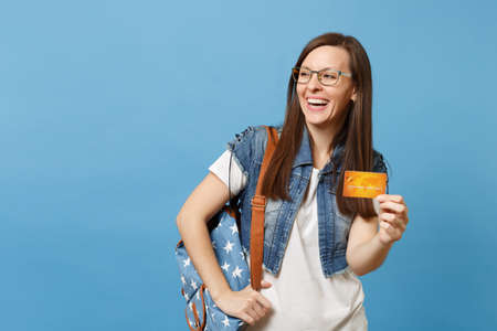 Portrait of young cute laughing woman student in denim clothes glasses with backpack looking aside...