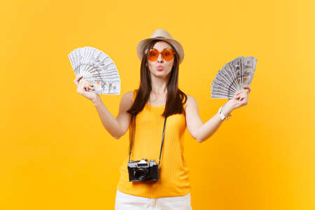 Tourist woman in summer casual clothes, hat holding bundle lots of dollars, cash money isolated on...