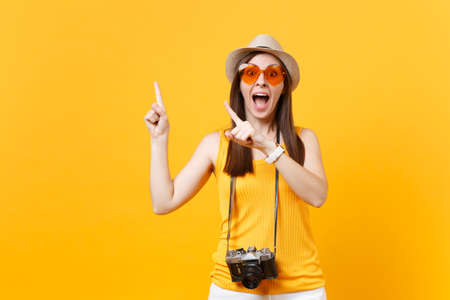 Tourist woman in summer casual clothes pointing index fingers aside isolated on yellow orange background. Female passenger traveling abroad to travel on weekends getaway. Air flight journey conceptの写真素材