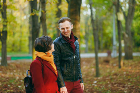 Young romantic couple in love cheerful woman, man in casual warm clothes walking by hands looking at each other in autumn city park outdoors in sunny day. Love relationship family lifestyle conceptの写真素材