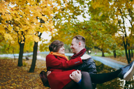 Young happy couple in love smiling man holding beautiful woman in his arms having fun looking at...