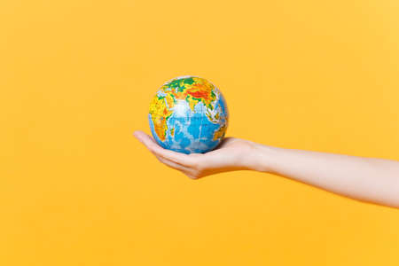 Close up female hold on hand palm Earth world globe isolated on yellow background. Air flight...