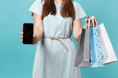 Portrait of woman in summer dress, straw hat holding packages bags with purchases after shopping,...