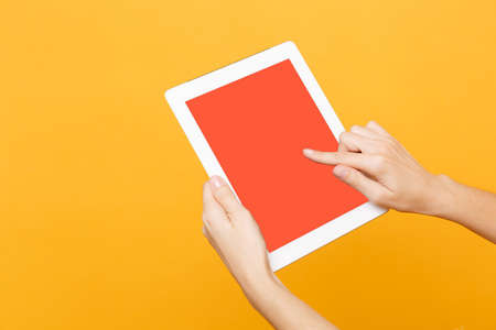 Close up female hold in hand tablet pc pad with blank empty screen with place for text or image, workspace isolated on trending yellow orange background. Technology concept. Copy space advertisementの写真素材