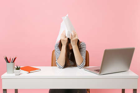 Exhausted woman holding paper documents near head lean on hands work on project while sitting at...
