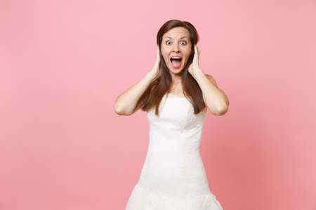 Portrait of excited shocked happy bride woman in beautiful white wedding dress standing clinging to...