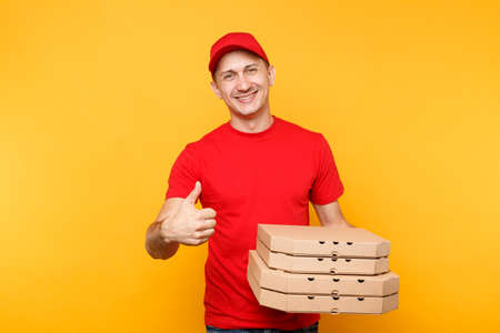 Delivery man in red cap, t-shirt giving food order pizza boxes isolated on yellow background. Male employee pizzaman or courier in uniform holding italian pizza in cardboard flatbox. Service conceptの写真素材