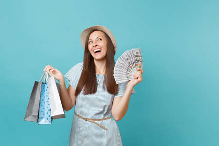 Portrait young woman in summer dress, straw hat holding packages bags with purchases after shopping,...