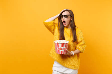 Shocked indignant young girl in 3d glasses putting hand on head, screaming watching movie film, hold...