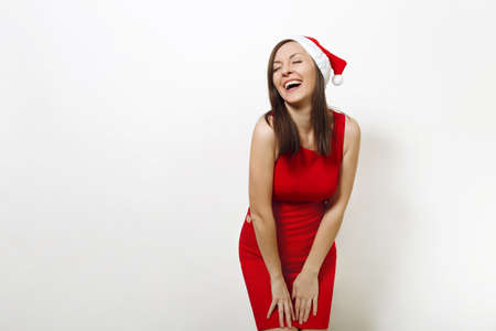 The beautiful caucasian young happy woman wearing red dress and Christmas hat laughing with her eyes closed with pleasure on white background.の写真素材