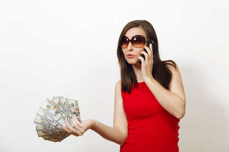 Pretty caucasian young happy business woman in red fitting dress and glasses talking on mobile...