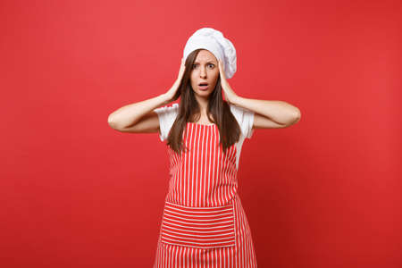Housewife female chef cook or baker in striped apron, white t-shirt, toque chefs hat isolated on red...