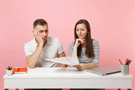 Two young tired business woman man colleagues sit work at white desk with contemporary laptop isolated on pastel pink background. Achievement career concept. Copy space advertising, youth co workingの写真素材