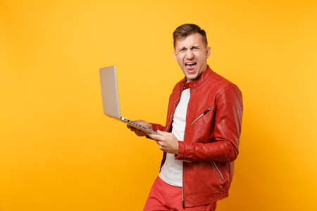 Portrait vogue fun handsome young man in red leather jacket, t-shirt using laptop pc tablet isolated...