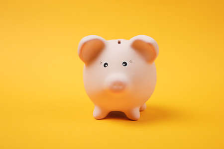 Close up photo of pink piggy money bank isolated on bright yellow wall background. Money...