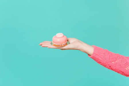 Close up female hold in hand pink cake isolated on blue turquoise wall background. Proper nutrition...