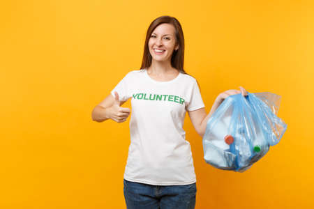 Woman in t-shirt volunteer, trash bag isolated on yellow background. Voluntary free assistance help, charity grace. Environmental pollution problem. Stop nature garbage environment protection conceptの写真素材
