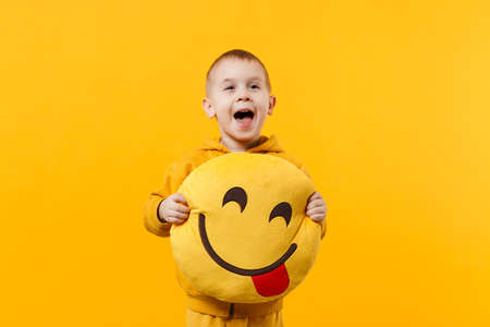 Little cute kid boy 3-4 years old wearing yellow clothes isolated on bright orange wall background, children studio portrait. People sincere emotions, childhood lifestyle concept. Mock up copy spaceの写真素材