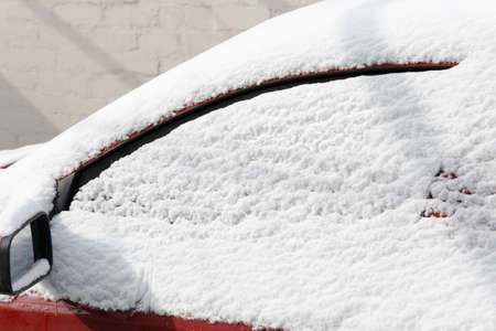 Close up of frozen red car covering with snow at winter day, side window on snowy background. Texture of snow and snowflakes for the New Year, winter holidays. Outdoors, nature conceptの写真素材